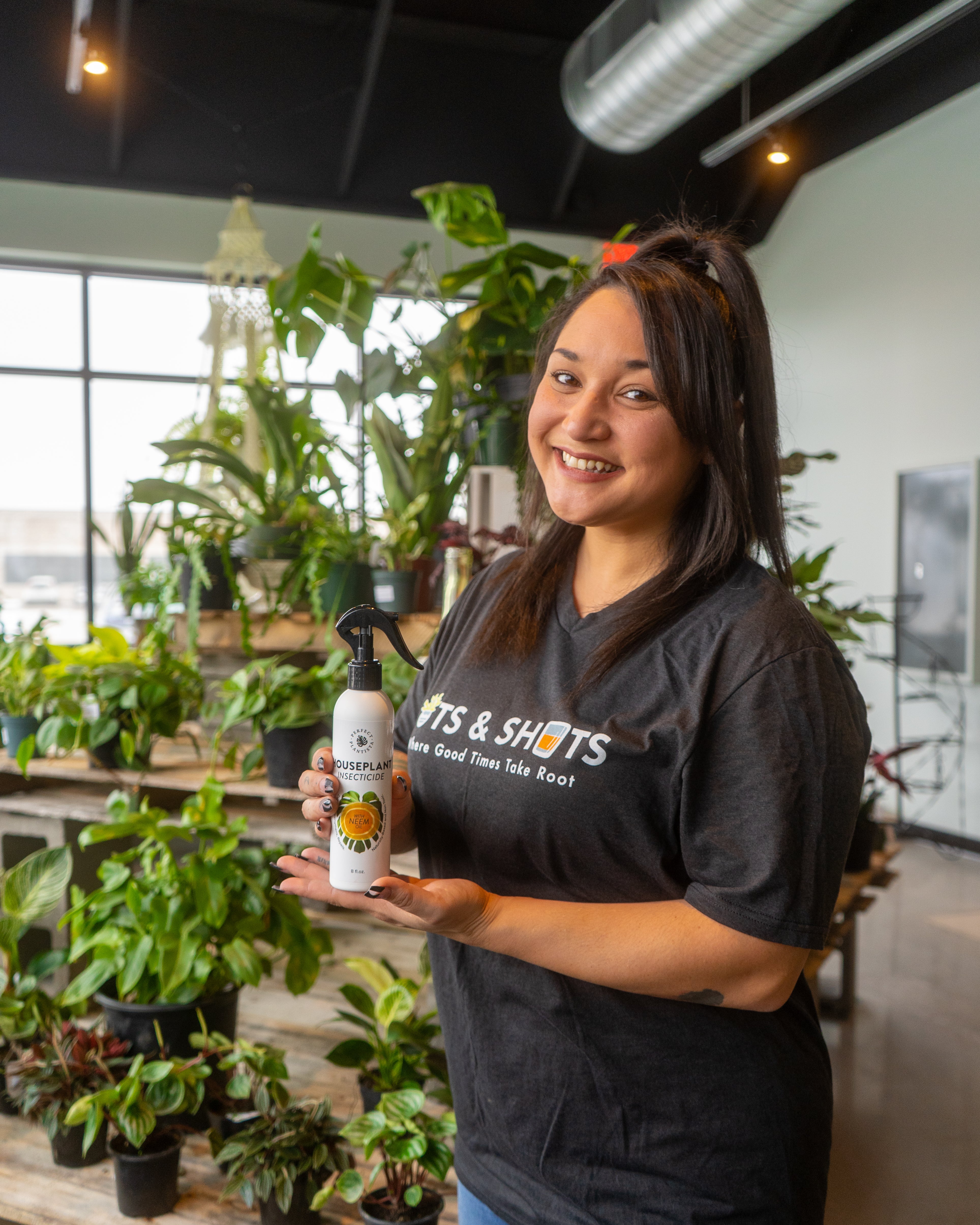 Temeshia Bomato, owner of Pots and Shots holding a bottle of Perfect Plantista's Houseplant Insecticide